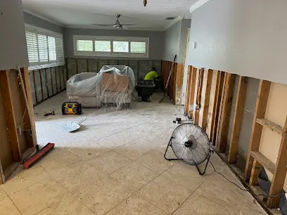 Flood-cut walls and a floor fan drying a gutted Punta Gorda living room