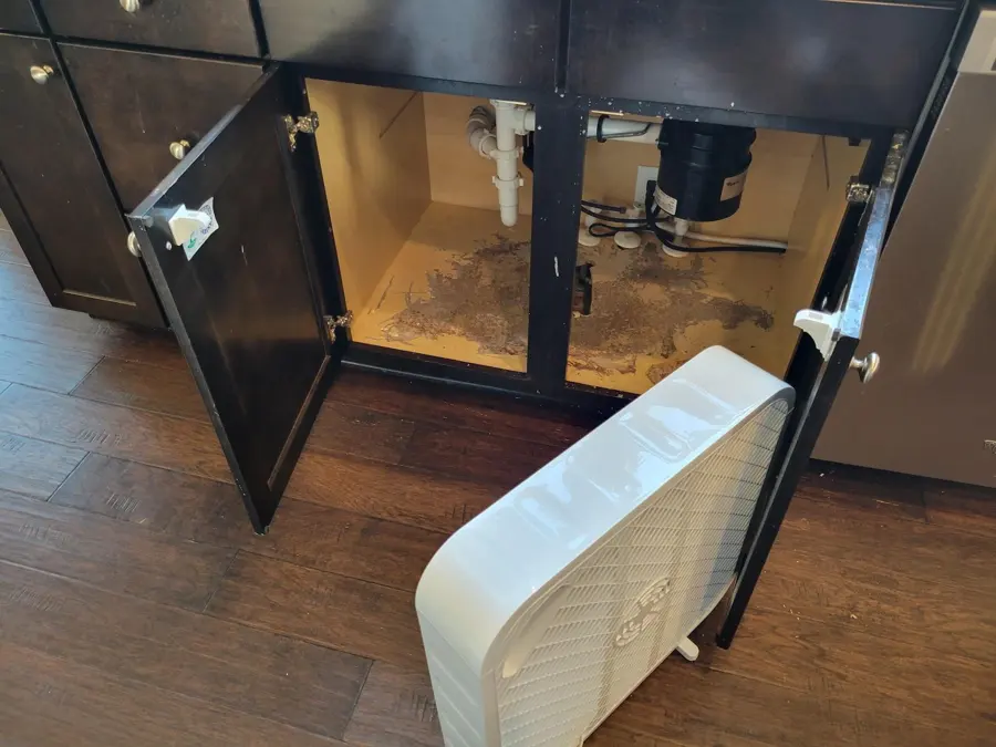 Fan drying a sink cabinet base after a kitchen leak in Punta Gorda